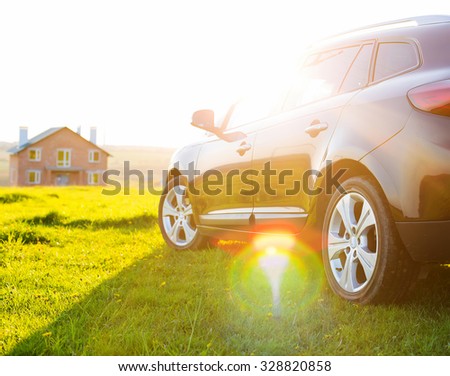 black car without a trade brand on grass at sunset