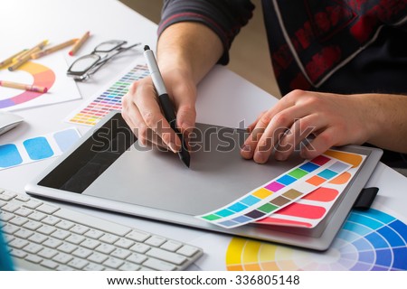 Young Handsome Graphic designer using graphics tablet to do his work at desk