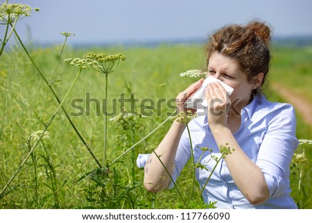 Woman with a flu or an allergy sneezing into her handkerchief in spring