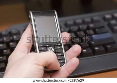 modern smartphone in hand of a caucasian man, keyboard background