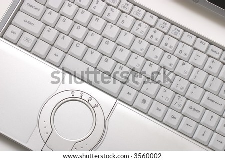 Keyboard of silvery hi-end modern laptop with round touchpad