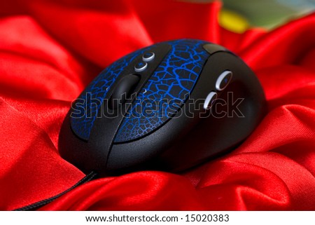 Modern computer mouse on red silk background. Studio shot.