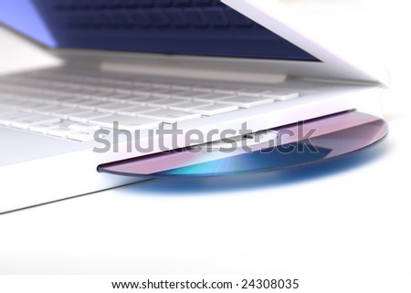 White laptop with optical disk in slot-loading drive. Isolated on a white background. Shallow DOF! Please use zoom tool for detail.