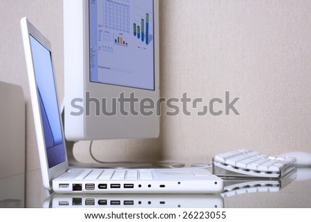 Modern elegance white laptop and computer screen on a glass desk. Laptop reflected on table. Selective focus on a laptop interface ports. Clipping path of screens for easy change its.