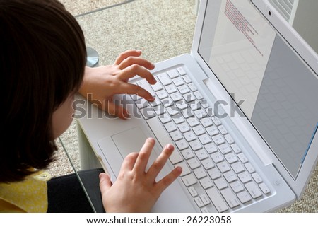 Caucasian girl 8 years old typing on white laptop. Above tilt view.