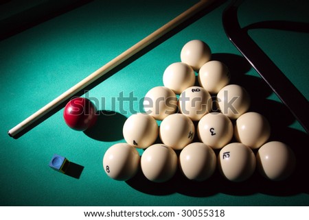 Pool balls on light beam. Balls pyramid with cue on a pool table.