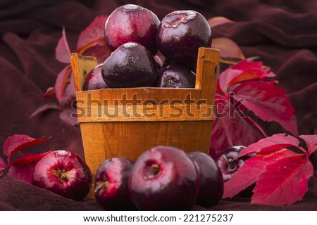 Ripe red apple red tubs wild grape leaves, ornamental background