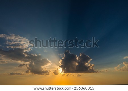 Sun behind the clouds and sea