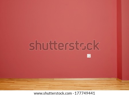 empty interior with wooden floor, plug and red wall