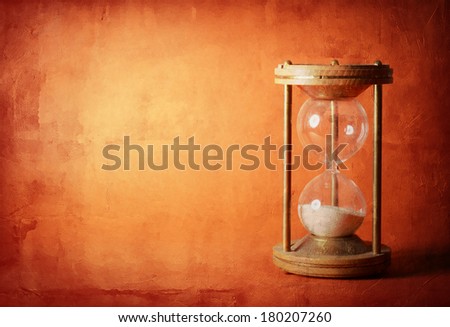 time concept with hourglass lying toned in warm orange and red colors, ancient sandglass