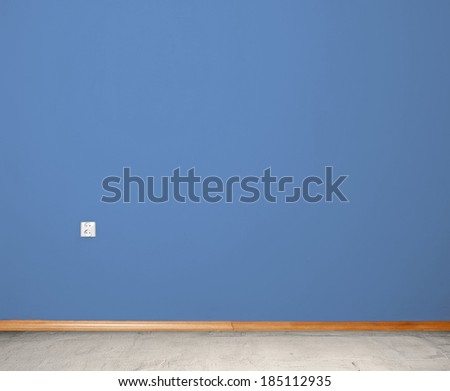 interior room with concrete floor and wall in blue with an electrical contact in the wall