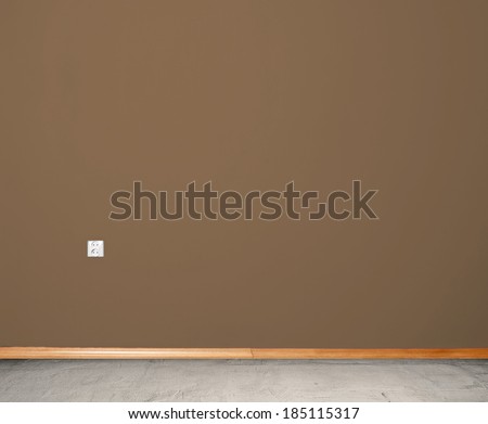 interior room with concrete floor and wall in brown with an electrical contact in the wall and wooden skirting