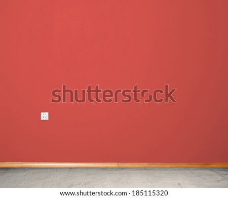 interior room with concrete floor and wall in red with an electrical contact in the wall and wooden skirting