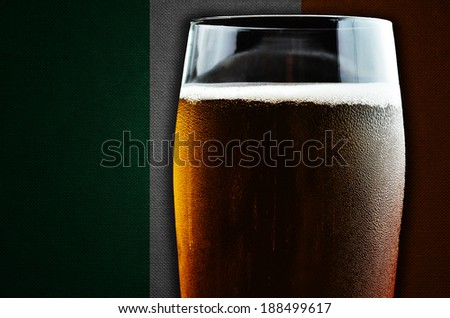 A glass of beer. Ireland flag in the background. One of the countries where beer consumption is highest in the world.