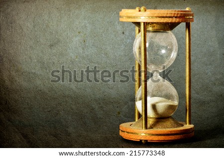 time concept with hourglass lying toned in warm dark colors on black background