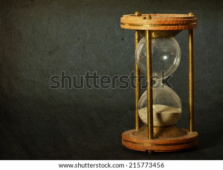 time concept with hourglass lying toned in warm dark colors on black background