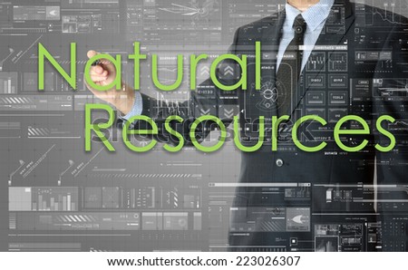 the businessman is writing Natural Resources on the transparent board with some diagrams and infocharts with the dark elegant background