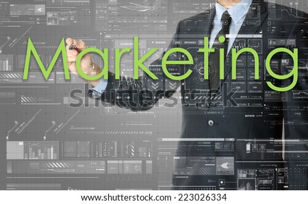 the businessman is writing Marketing on the transparent board with some diagrams and infocharts with the dark elegant background