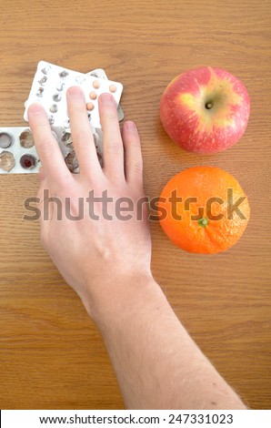 Healthy food. Fresh fruits and vegetables versus medical pills on table. The hand is choosing medicines