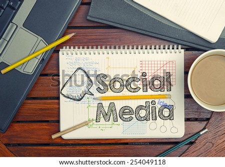 Notebook with text inside Social Media on table with coffee, notebook and pencils