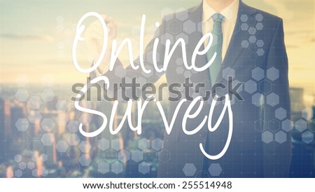 businessman write on transparent board Online Survey with sunset over the city in the background, the sun\'s rays falling into lens are symbolizing the good attitude
