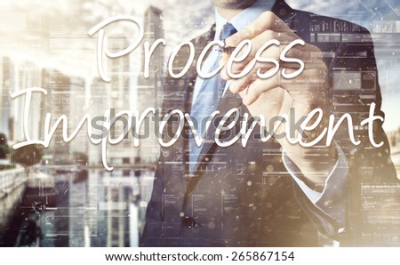 businessman writing Process Improvement on transparent board with city in background