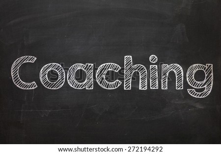 The word Coaching handwritten with white chalk on a blackboard