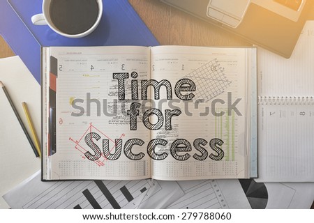 Notebook with text inside Time for success on table with coffee, some diagrams on paper and laptop