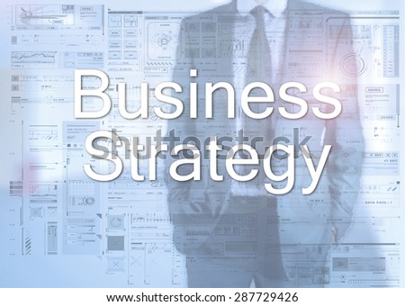 Businessman standing behind transparent board with diagrams and text Business Strategy
