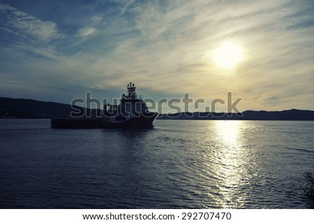 Cargo ship sailing away against colorful sunset