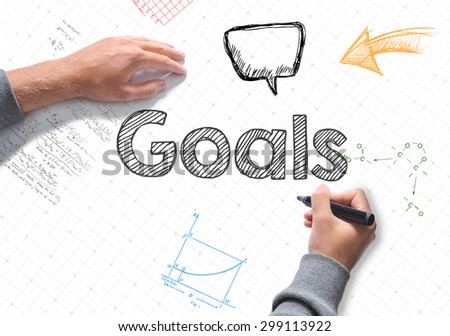 Hand writing Goals word on white sheet of paper
