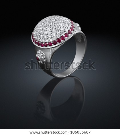 Silver ring with diamonds and red gems on black background