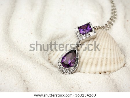 jewelry pendant with gems and diamonds on sand background