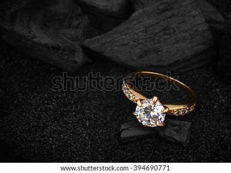 jewelry ring witht big diamond on dark coal and black sand background