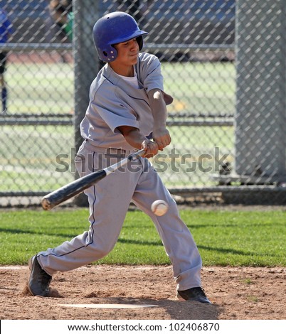 A youth baseball player swings at a ball over the plate.