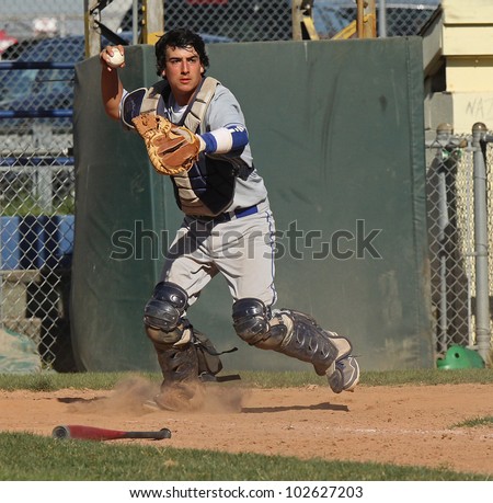A baseball catcher throws to first base to check the runner.