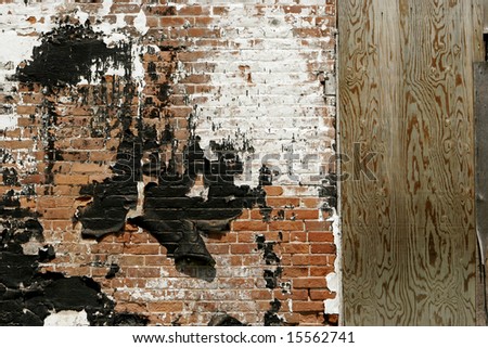 Brick wall of old abandoned factory with peeling paint. Copy space on boarded up door.