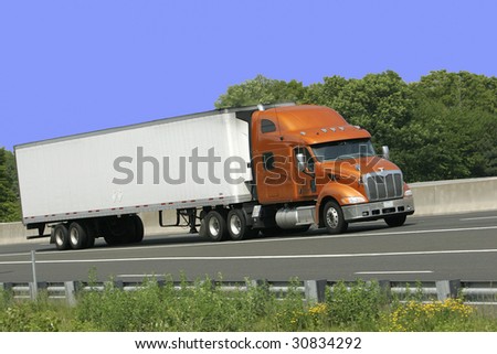 White trailer truck with orange cab against blue sky. Plenty of copy space.