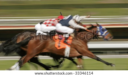 Three horses running neck and neck toward the finish line. Slow shutter speed to enhance motion and speed effect.