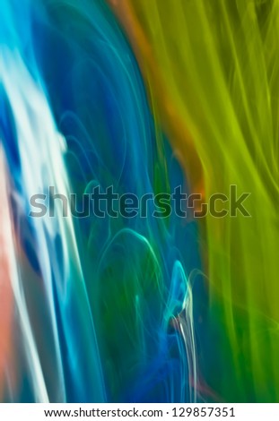 Background of blue, green, white and orange, ink dye in water, macro.