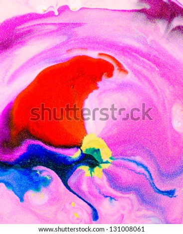 Macro of vivid pink, red and blue ink flowing over white liquid, with gold metallic glitter.