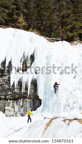 JOHNSTON CANYON, BANFF, CANADA - MARCH 26: Instructor Will Gadd belays during a lesson, teaching a student  to ice climb at the Upper Falls of Johnston Canyon, March 26, 2013 in Banff , AB, Canada.