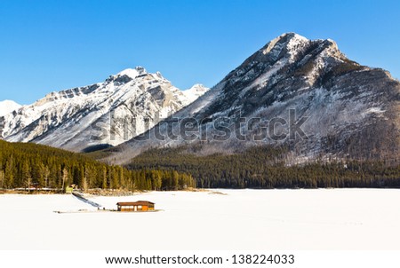 Fueling station,closed for the season, frozen in the ice and snow in the winter on Lake Minnewanka, against the backdrop of the majestic Rocky Mountains of Banff National Park, Canada