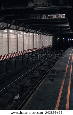 Deserted underground subway platform and tracks in New York City. Processed with added grain