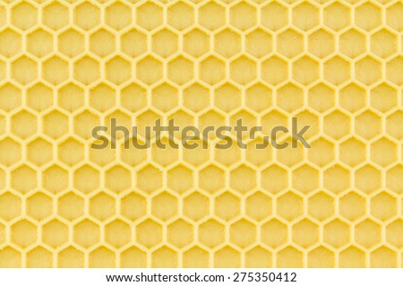 Close up of wax coated plastic honeycomb foundation.  Yellow hexagon pattern background.