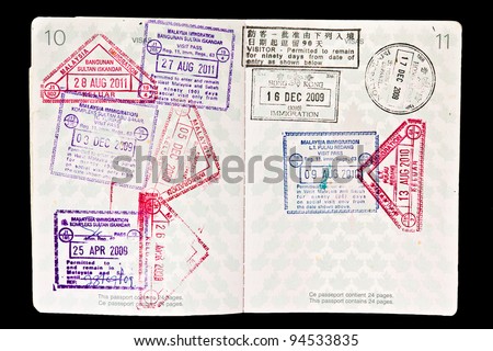 Multiple entries into Malaysia resulting in many entry and exit stamps in a Canadian passport. Isolated on black. Passport full and canceled with corner cut off.