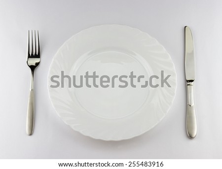 Top view of white plate with silver fork and knife with place for your object
