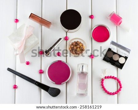 Fashion woman objects. Makeup and cosmetic set: lipstick, foundation, concealer, eyeshadow palette, blusher balls, perfume on white wooden background