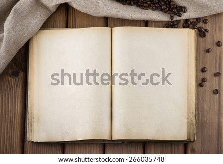 Top view of blank old book with sackcloth and cofee beans on wooden background