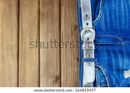 Top view of female jeans with belt on wooden background with place for your text